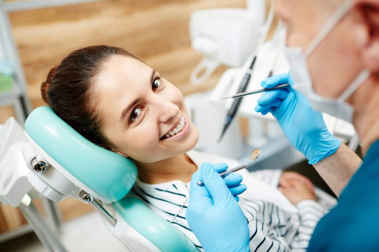 Woman smiles in dentist chair before dental hygienist cleans and exams her teeth
