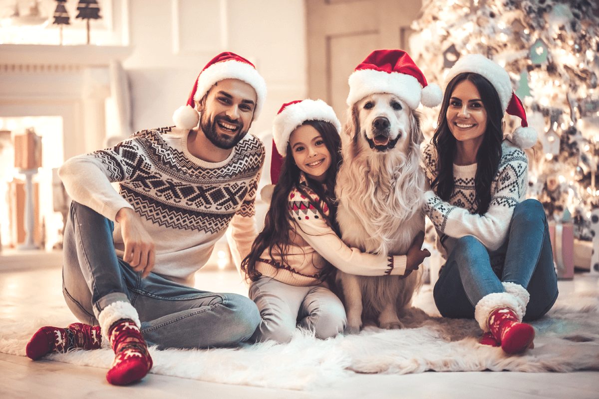 Family wears Christmas hats and sweaters and smiles at camera