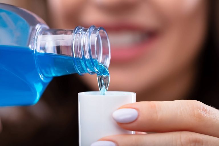Woman pours mouthwash into plastic cup to protect teeth from cavities