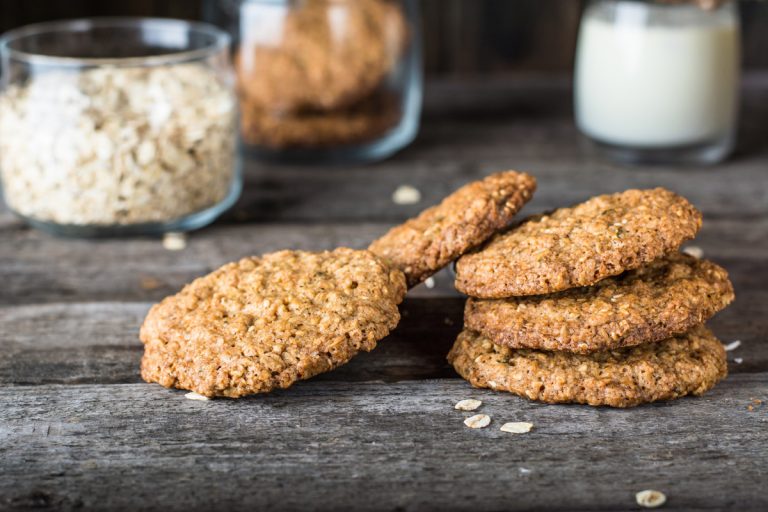 Oatmeal cookies on the kitchen table with a glass of milk in the background