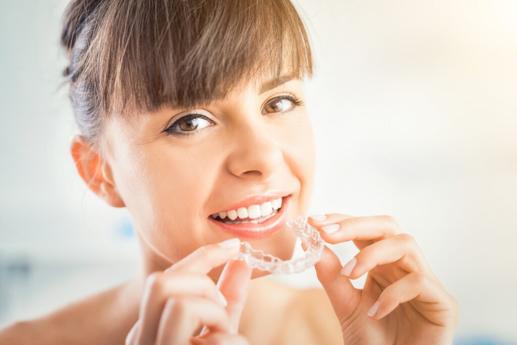 a girl is holding the clear aligners