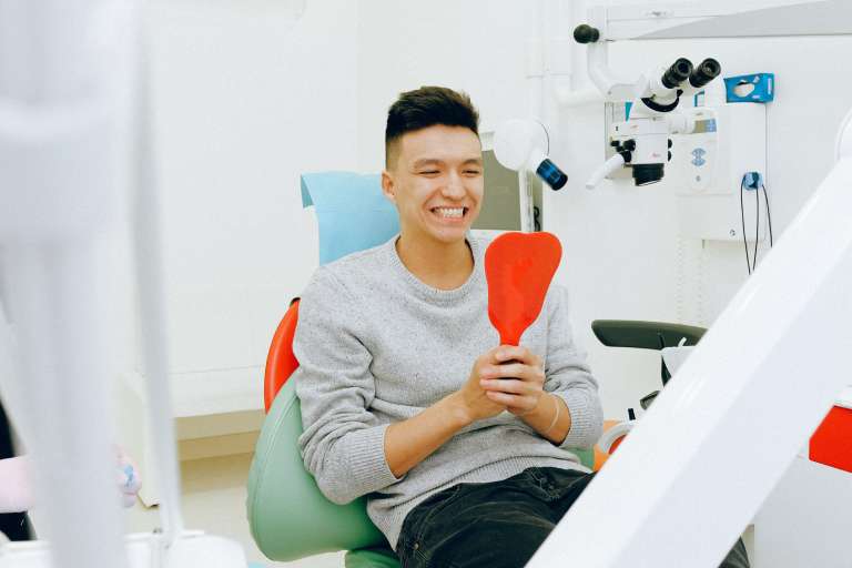 a person is checking his teeth after dental crown replacement