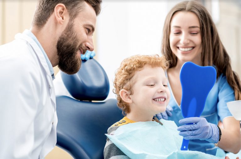 a child is watching his teeth in the mirror