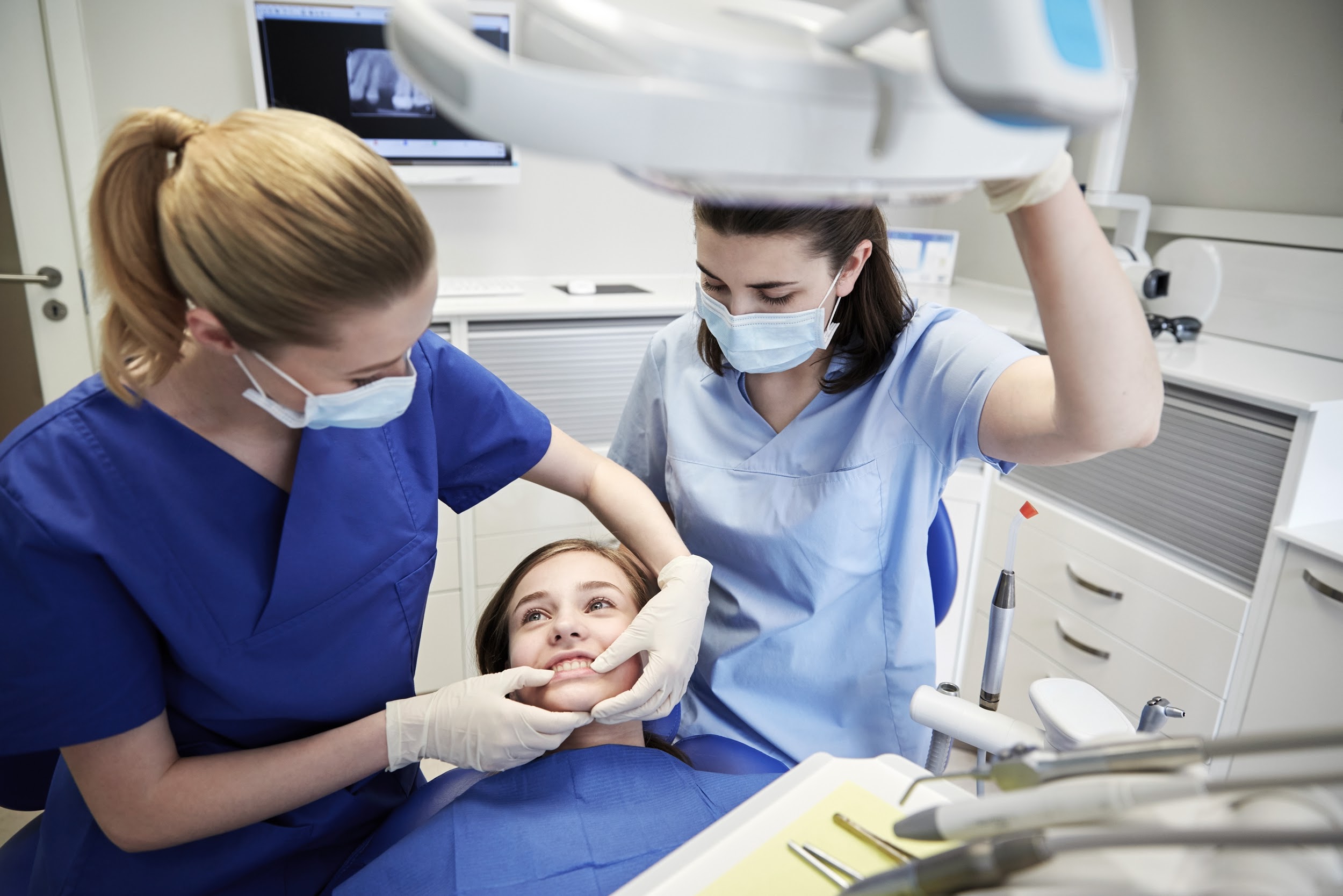 a dentist is checking the teeth of girl child