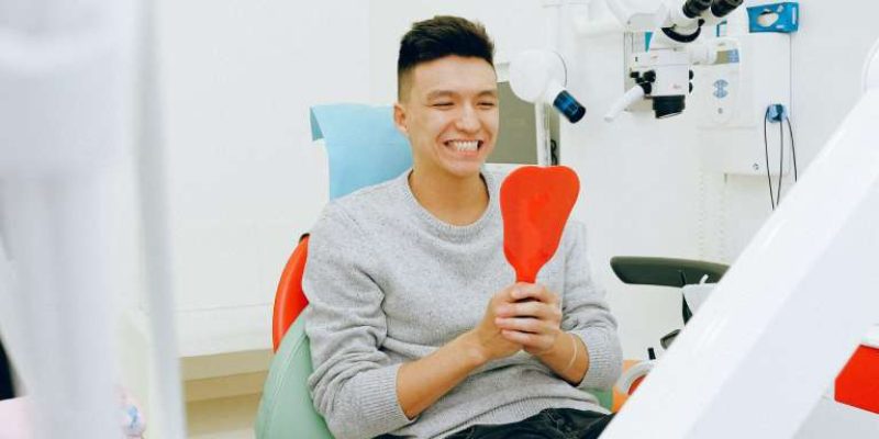 a person is checking his teeth after dental crown replacement